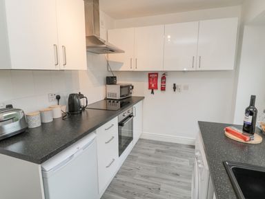A kitchen with white cabinets black countertops microwave kettle and toaster at Lavender Cottage in Glanton