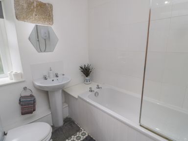 A bathroom with a bathtub a sink a toilet a towel and a mirror at Lavender Cottage in Glanton