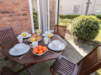 An outdoor wooden table set with plates bowls croissants oranges and glasses of orange juice at Seadrift The Bay near Filey