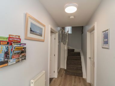 A hallway with a staircase, doors, framed pictures on walls, and a brochure rack at Seadrift The Bay near Filey