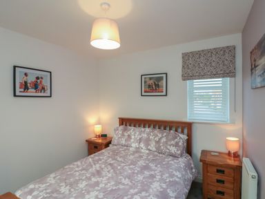 A bedroom with a wooden bed and matching bedside tables with lamps at Seadrift The Bay near Filey