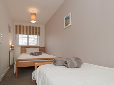 A bedroom with two single beds and rolled towels on each at Seadrift The Bay near Filey