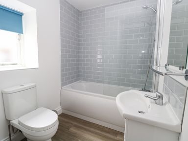 A bathroom with a toilet sink and bathtub with tiled walls at Waveney View Cottage in Burgh Castle
