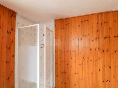A shower enclosure with tiled walls and wood paneling in a bathroom at Lawn Farm Cottage Churcham near Gloucester