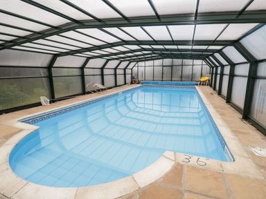 An indoor swimming pool with tiled floor and transparent roof at Lawn Farm Cottage in Churcham near Gloucester