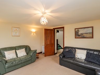 A living room with two leather sofas cushions wall art and a wooden door at Lawn Farm Cottage Churcham near Gloucester