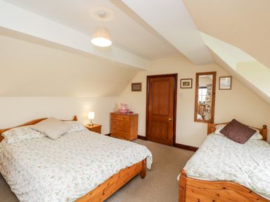 A bedroom with two beds a wooden dresser a nightstand and a door at Lawn Farm Cottage Churcham near Gloucester