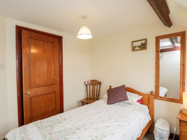 A bedroom with a single bed pillow wooden chair mirror and closed wooden door at Lawn Farm Cottage in Churcham near Gloucester