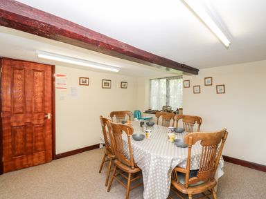 A dining room with wooden chairs and a polka dot tablecloth at Lawn Farm Cottage in Churcham near Gloucester