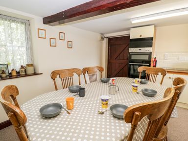 A dining room with wooden chairs around a polka dot covered table set with bowls and cups at Lawn Farm Cottage Churcham near Gloucester