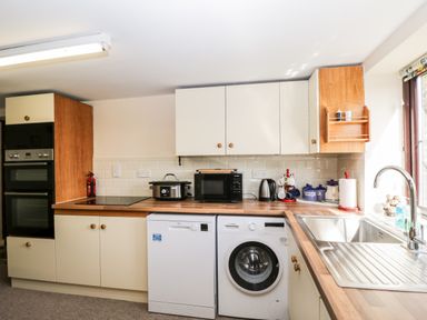 A kitchen with appliances including oven microwave kettle washing machine and dishwasher at Lawn Farm Cottage in Churcham near Gloucester
