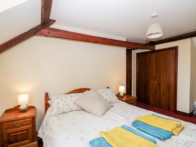 A bedroom with a double bed two bedside tables with lamps and folded towels on the bed at Lawn Farm Cottage in Churcham near Gloucester