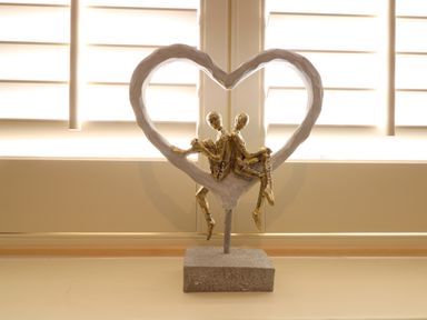 A sculpture of two abstract figures sitting back to back inside a heart shape on a windowsill at Captains Cottage in Sheringham