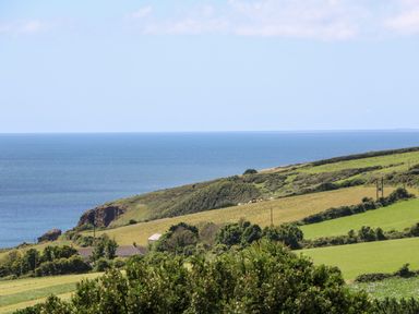 A coastal landscape with green fields and bushes overlooking the ocean at Atlantic View in Germoe