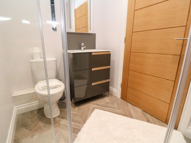 A bathroom with a toilet towels on top a sink cabinet and a wooden door at Atlantic View in Germoe