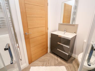 A bathroom with a wooden door a sink with cabinet a mirror and a toilet at Atlantic View in Germoe