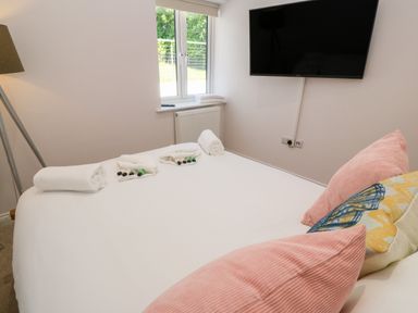 A bedroom with a bed with pillows and rolled towels under a wall-mounted TV at Atlantic View in Germoe