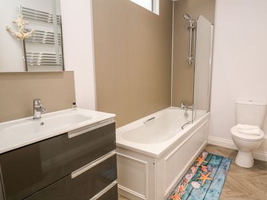 A bathroom with a bathtub shower combination a sink with a cabinet and a toilet at Atlantic View in Germoe