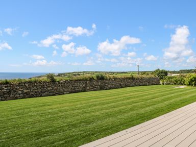 A green lawn with a stone wall and ocean view at Atlantic View in Germoe
