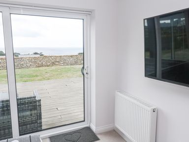 A living room with a sliding door and television at Atlantic View in Germoe