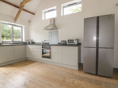 A kitchen with wooden floor white cabinets stainless steel oven refrigerator microwave and toaster at The Corn Store in St Stephen