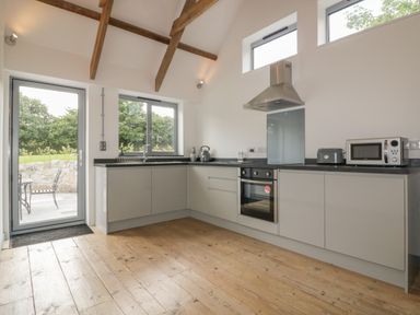 A kitchen with wooden floor and ceiling beams and appliances at The Corn Store in St Stephen