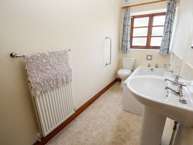 A bathroom with a sink bathtub toilet window and a radiator with a towel at The Onibury in Craven Arms