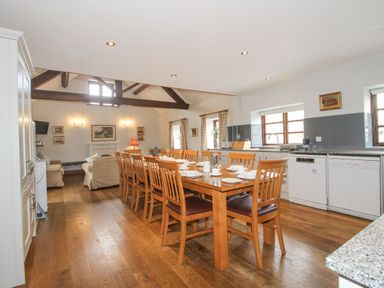 A kitchen and dining area with a long wooden table and chairs and a seating area at The Onibury in Craven Arms