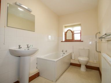 A bathroom with a sink a bathtub a toilet a mirror and a window at The Onibury in Craven Arms