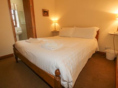 A bedroom with a wooden bed with white bedding and towels placed on it at The Onibury in Craven Arms