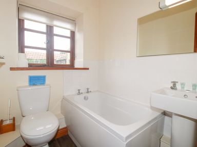 A bathroom with a toilet bathtub sink and a window at The Onibury in Craven Arms