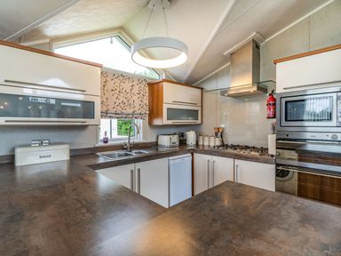 A kitchen with a sink toaster kettle stove oven and microwave at Links Lodge in Flookburgh