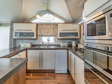 A kitchen with cabinets a sink a dishwasher a toaster a kettle and an oven at Links Lodge in Flookburgh