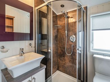 A bathroom with a shower enclosure sink with cabinet mirror and toilet at Links Lodge in Flookburgh