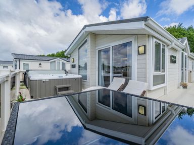 A patio area with outdoor hot tub dining table and chairs at Links Lodge in Flookburgh