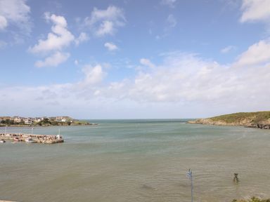 A coastal view with a harbor and houses on the left and rocky hills on the right at Monfa in Cemaes Bay