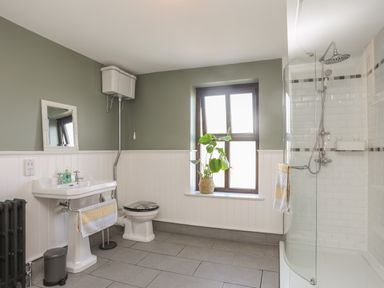A bathroom with a toilet a sink a shower and a window with a plant at Monfa in Cemaes Bay