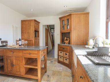 A kitchen with wooden cabinets granite countertops a kitchen island and a sink near a window at Monfa in Cemaes Bay