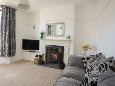 A living room with a fireplace television gray sofa and floral curtains at Monfa in Cemaes Bay