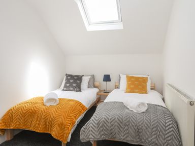 A bedroom with two single beds with throws and pillows and a skylight at Monfa in Cemaes Bay