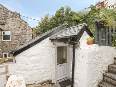 A white stone building with a small roof and a door at Glan Meon Cottage in Barmouth
