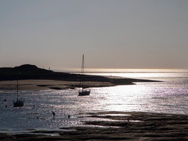 A coastal scene with sailboats on water and people near the shore at Glan Meon Cottage in Barmouth
