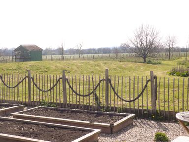 A garden with raised planting beds fenced by a wooden fence with rope at Tiny Willow in Farrington near Child Okeford