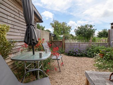 A garden with a table and chairs at Tiny Willow in Farrington near Child Okeford