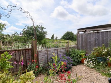 A garden with flowers and an archway at Tiny Willow in Farrington near Child Okeford