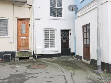 A small courtyard with three doors and two windows on the surrounding buildings at Bay Tree Cottage in West Looe