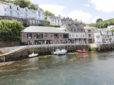 A waterfront with boats moored in the water and buildings along the shore at Bay Tree Cottage in West Looe