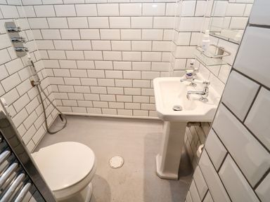 A small bathroom with a toilet a pedestal sink and hand shower at Bay Tree Cottage in West Looe
