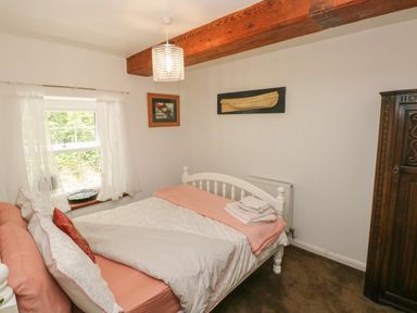 A bedroom with a white bed near a window with curtains and an ornate wooden wardrobe at The Old Mill in Neyland near Milford Haven