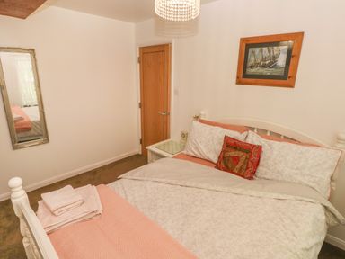 A bedroom with a bed featuring patterned bedding and a pillow a wooden door a mirror on the wall and a bedside table at The Old Mill in Neyland near Milford Haven